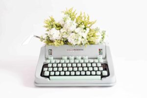 a typewriter with a bunch of flowers on top of it