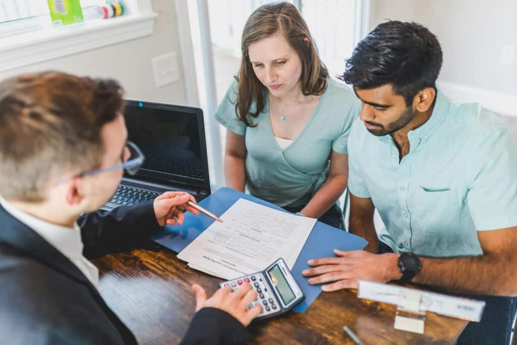 a man and woman sitting at a table with papers and a calculator
