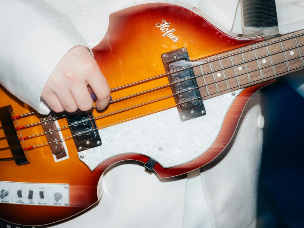 Person playing a vintage hofner bass guitar.