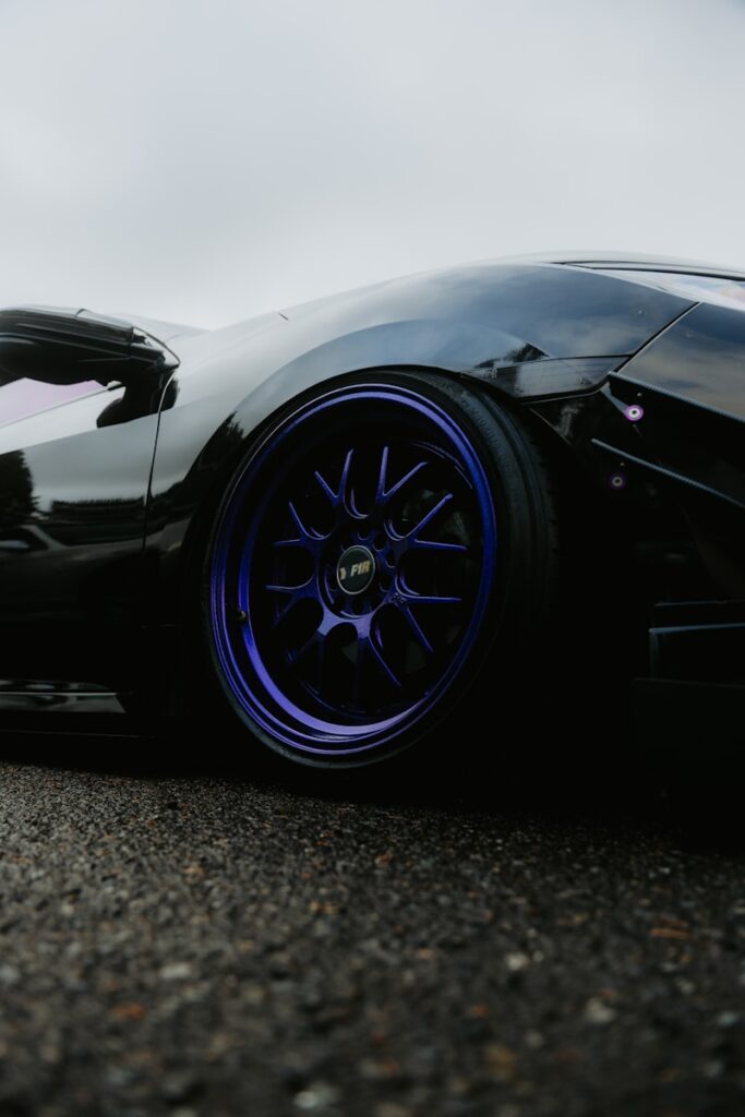 A close-up of a shiny, blue-wheeled car.