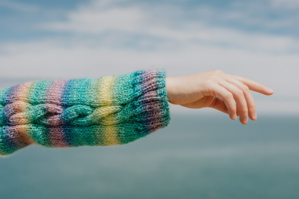A hand reaches out with a colourful sweater.