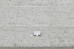 A man walking down a street next to a cement wall
