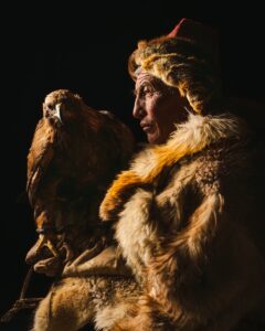 A man holds a falcon, traditional clothing.
