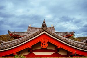 Beautiful shot of a traditional Japanese temple roof with intricate design under a cloudy sky.