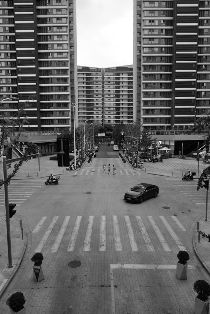 Black and white photo of a city intersection framed by tall symmetrical buildings.