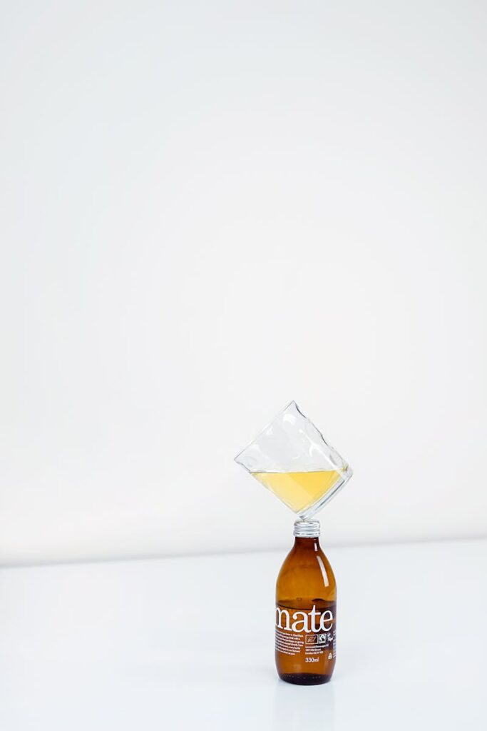 A minimalist photo featuring a balancing glass and bottle with a white background, showcasing creativity.