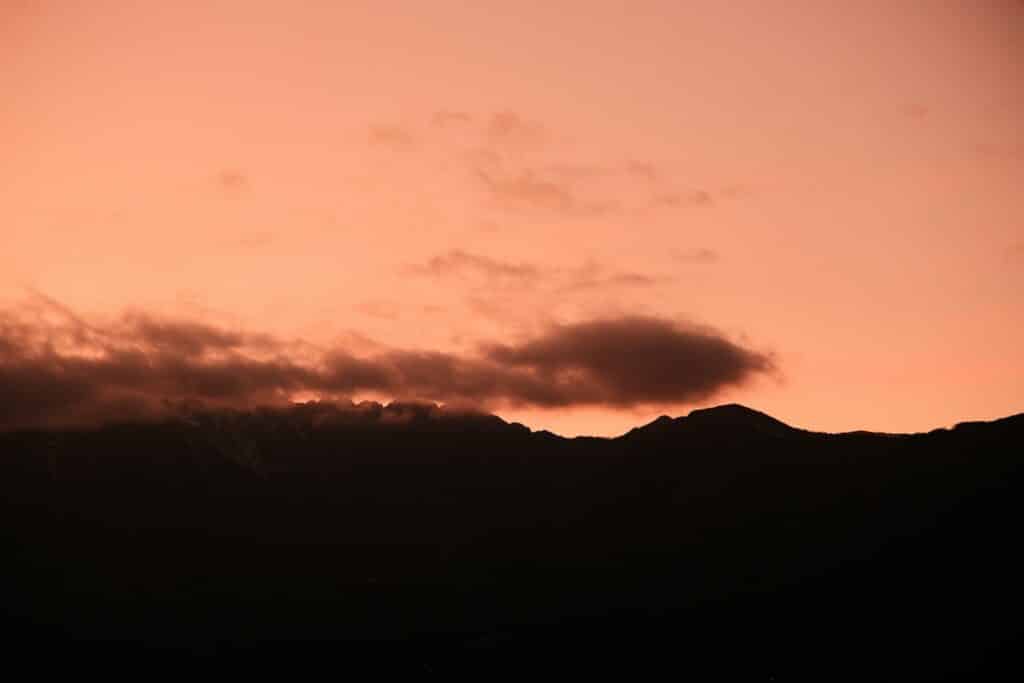Orange sunset over dark mountains and clouds.