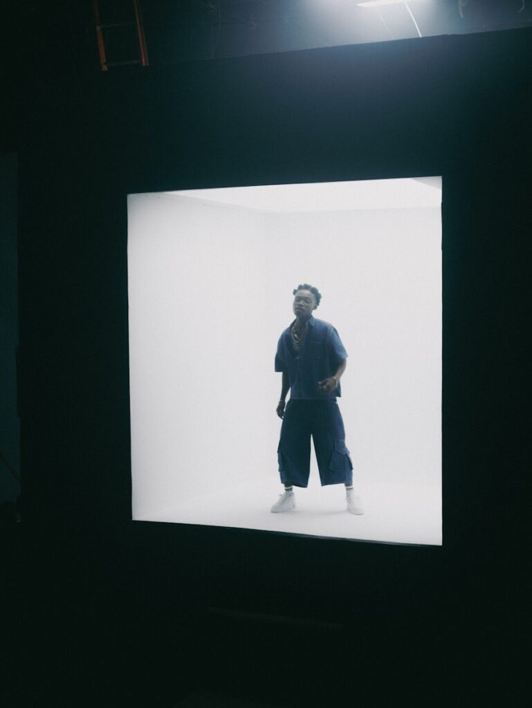 A man stands inside a bright white box.