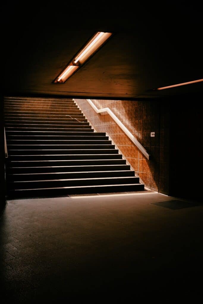 Stairs lead to light in a dark subway.