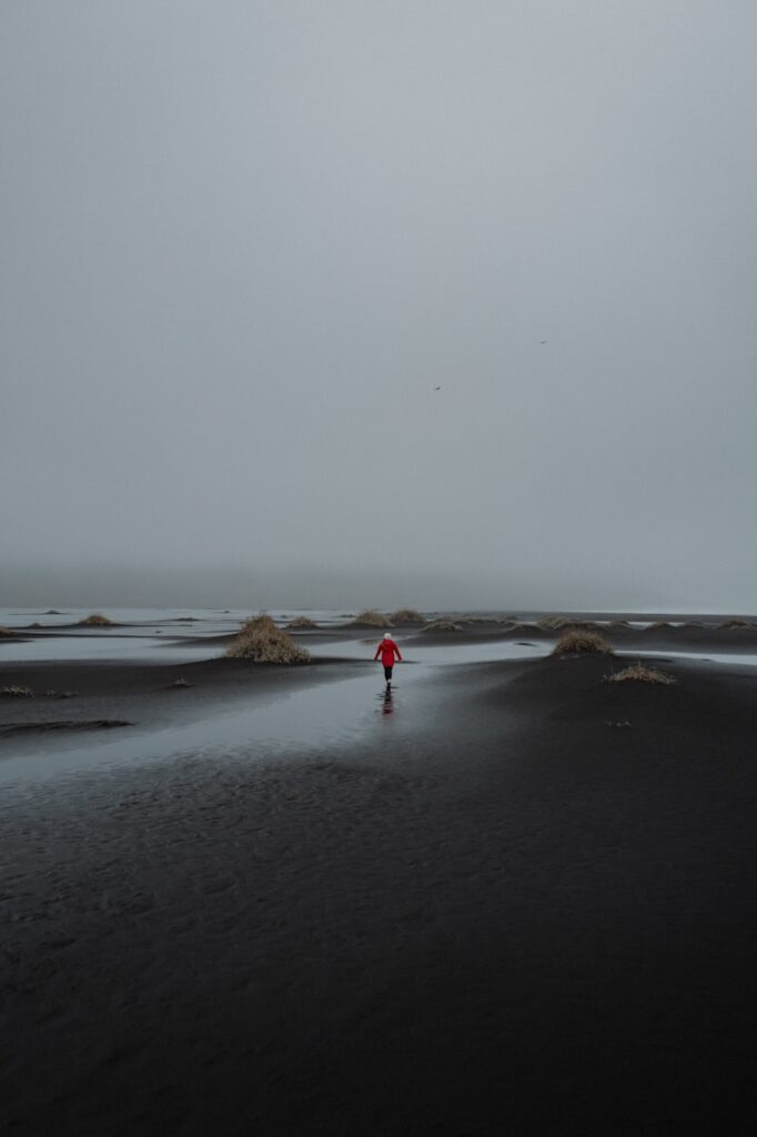 A person in red walks across a black landscape.