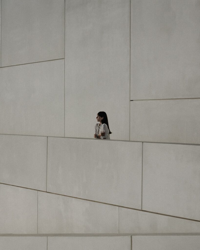 Girl stands observing a geometric, modern facade.