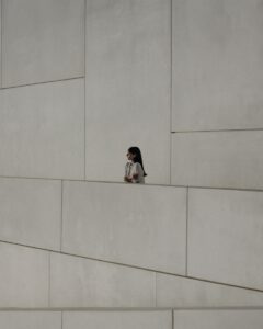 Girl stands observing a geometric, modern facade.