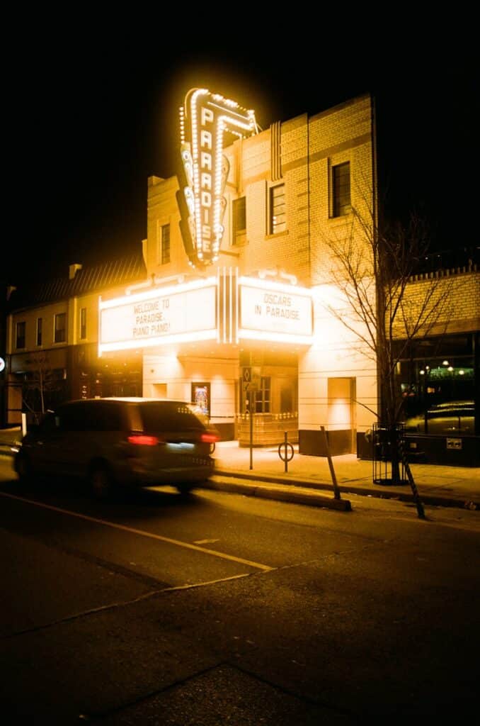The paradise theatre glows at night with moving cars.