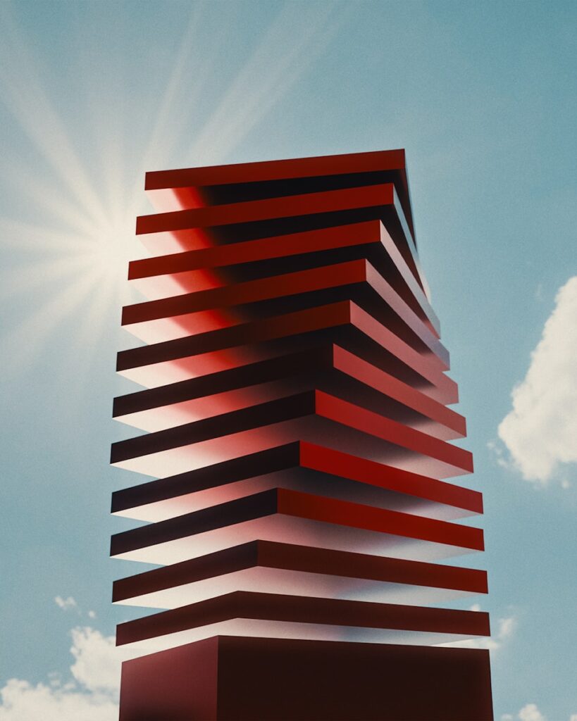 Red layered tower against a bright sun and sky.