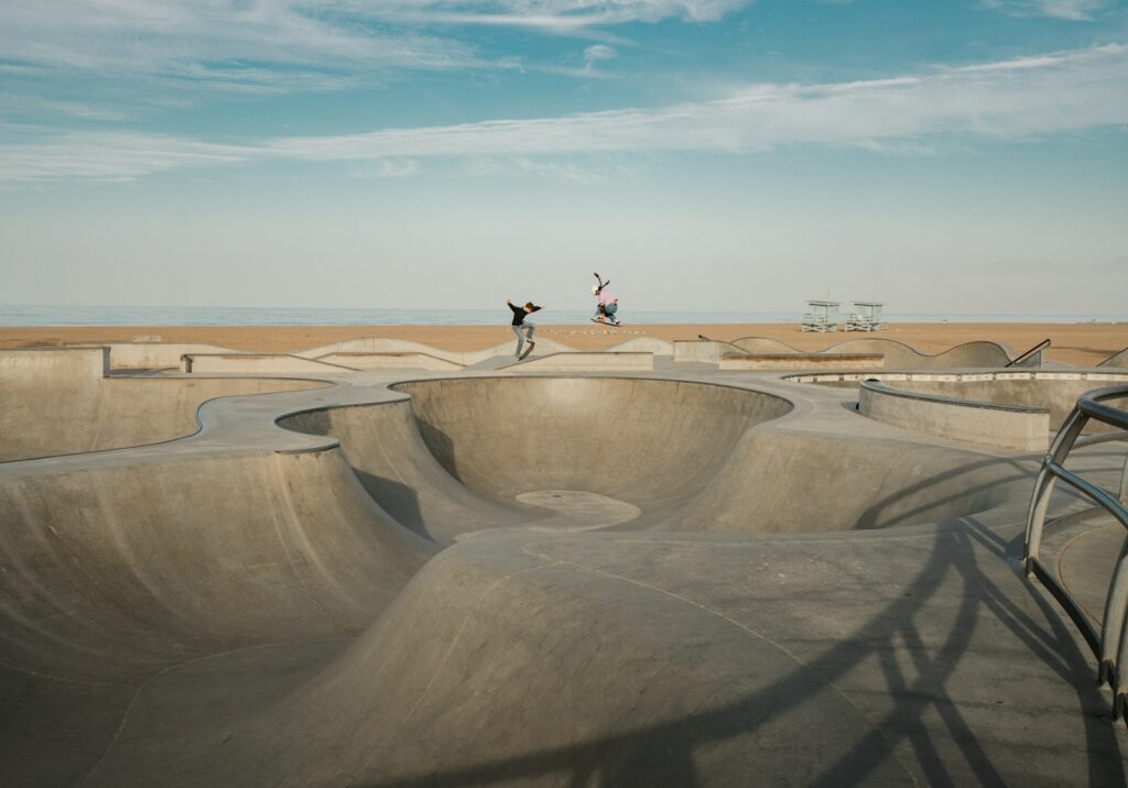 Skaters ride a concrete skatepark on a sunny day.
