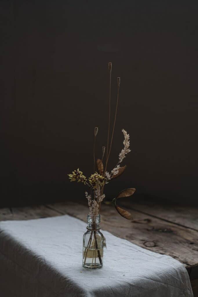 Dried flowers in a vase sit on a table.