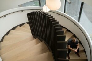 Person sitting on a modern, winding staircase.