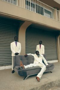 Three men in suits pose outside.