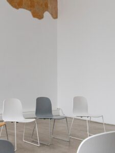Chairs sit in a minimalist white-walled room.
