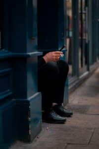 A person is crouching and using a phone.