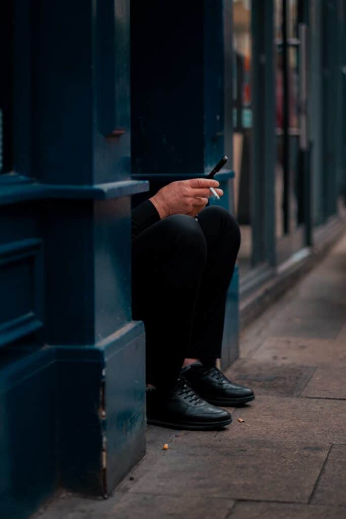 A person is crouching and using a phone.