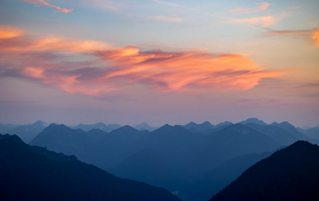 Mountains stand below a colourful sunset.