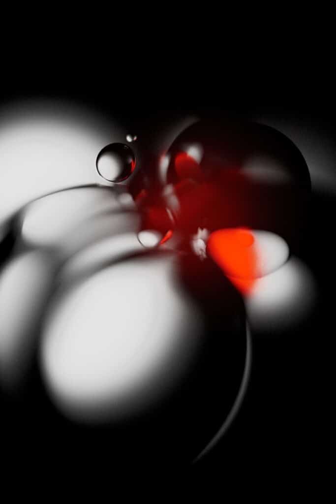 Glowing spheres in grayscale with red highlight.