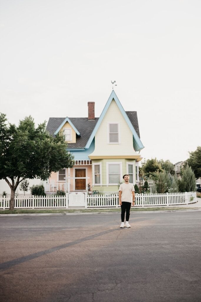Man stands in front of a colorful house.