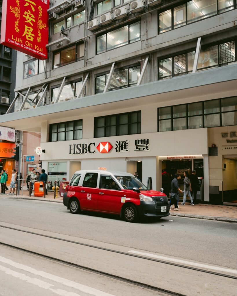 A red taxi in front of an hsbc bank.
