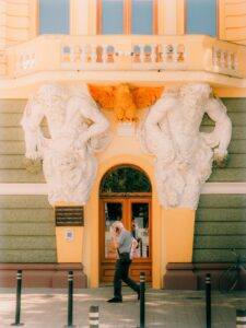 Man walks past ornate building entrance.