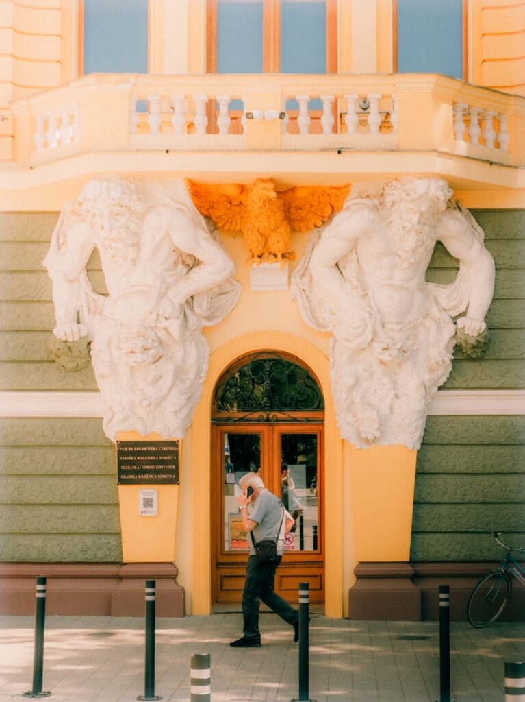 Man walks past ornate building entrance.