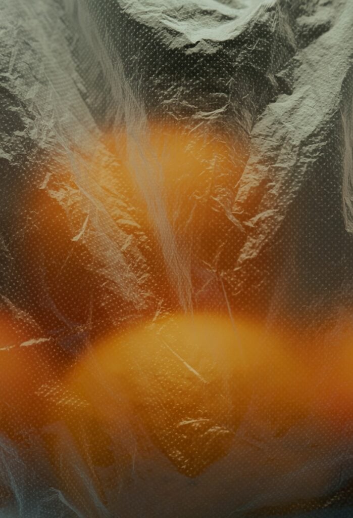 Oranges are seen through a plastic bag.