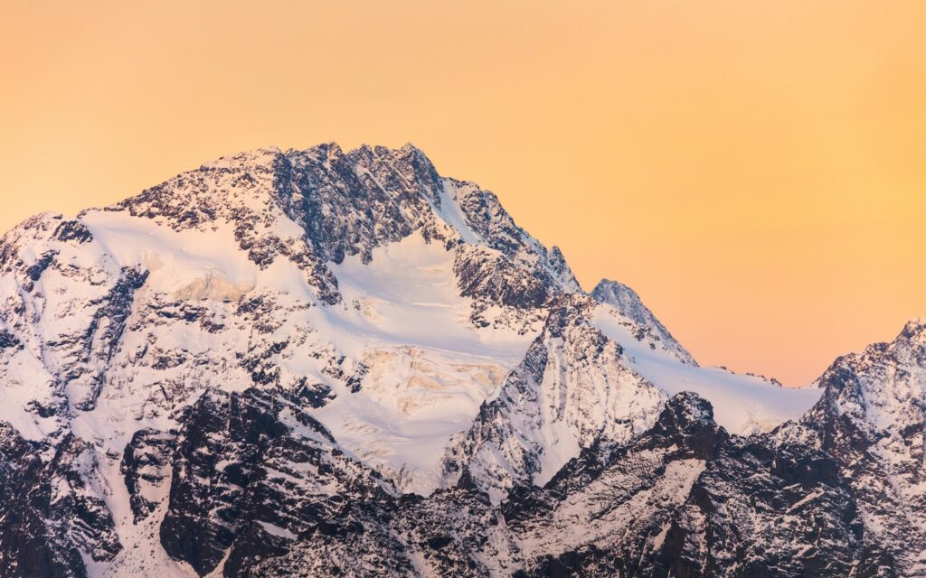 Snow-capped mountains against an orange sky.