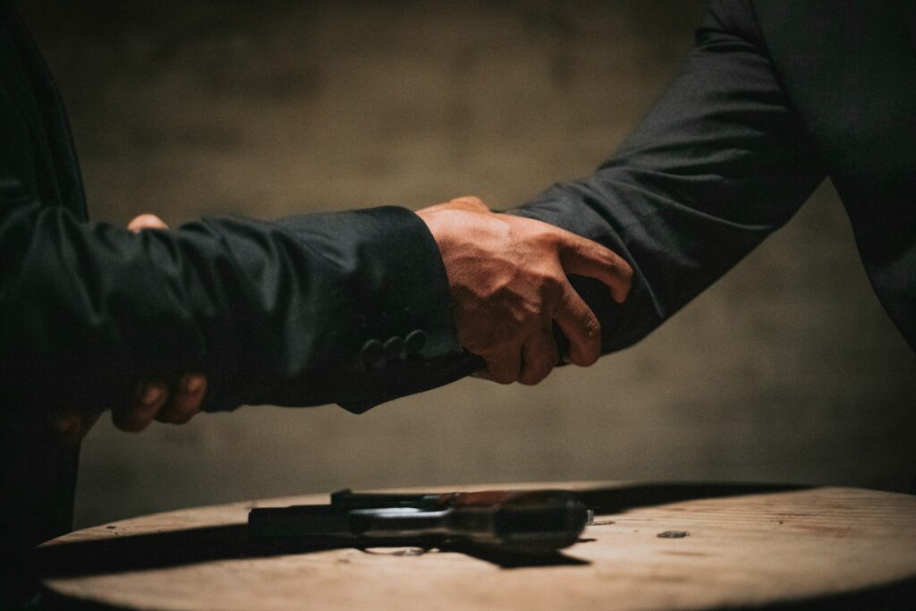 two people shaking hands over a wooden table