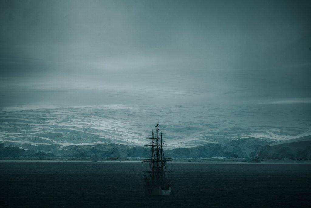 A ship sails in a cold, icy seascape.