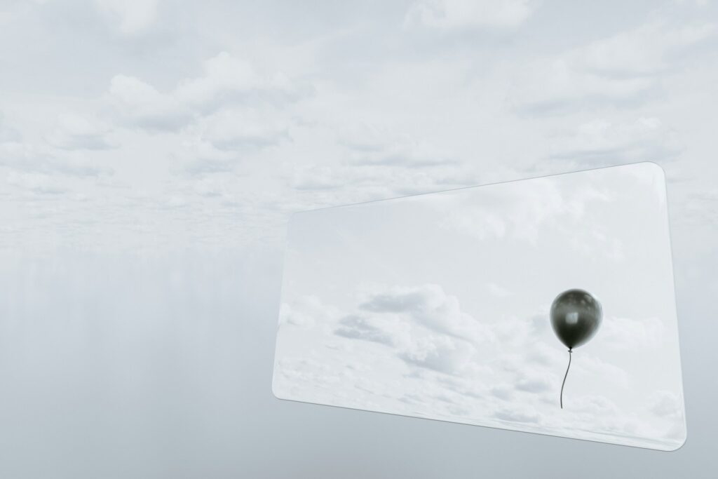 A balloon floats against a cloudy sky.