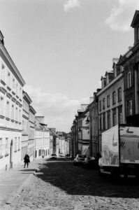 Buildings line a street under a cloudy sky.