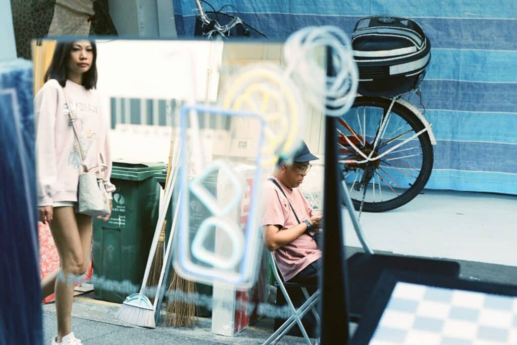 Woman walks by a reflective street scene.