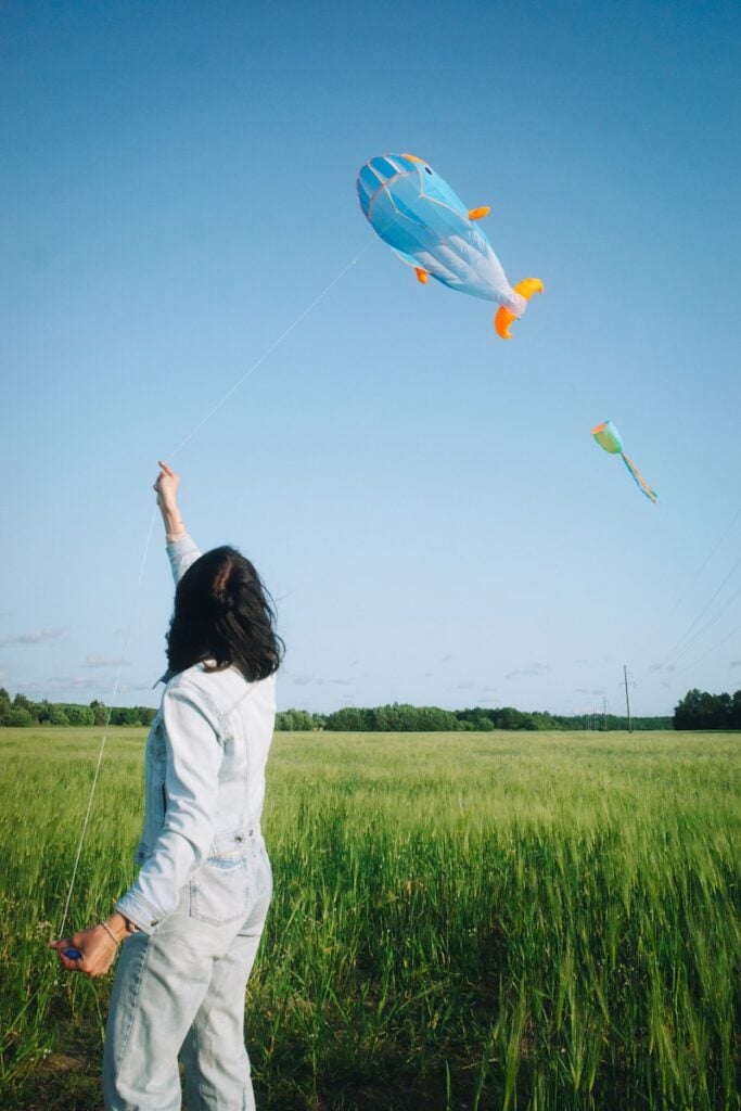 A woman flies kites in a green field.