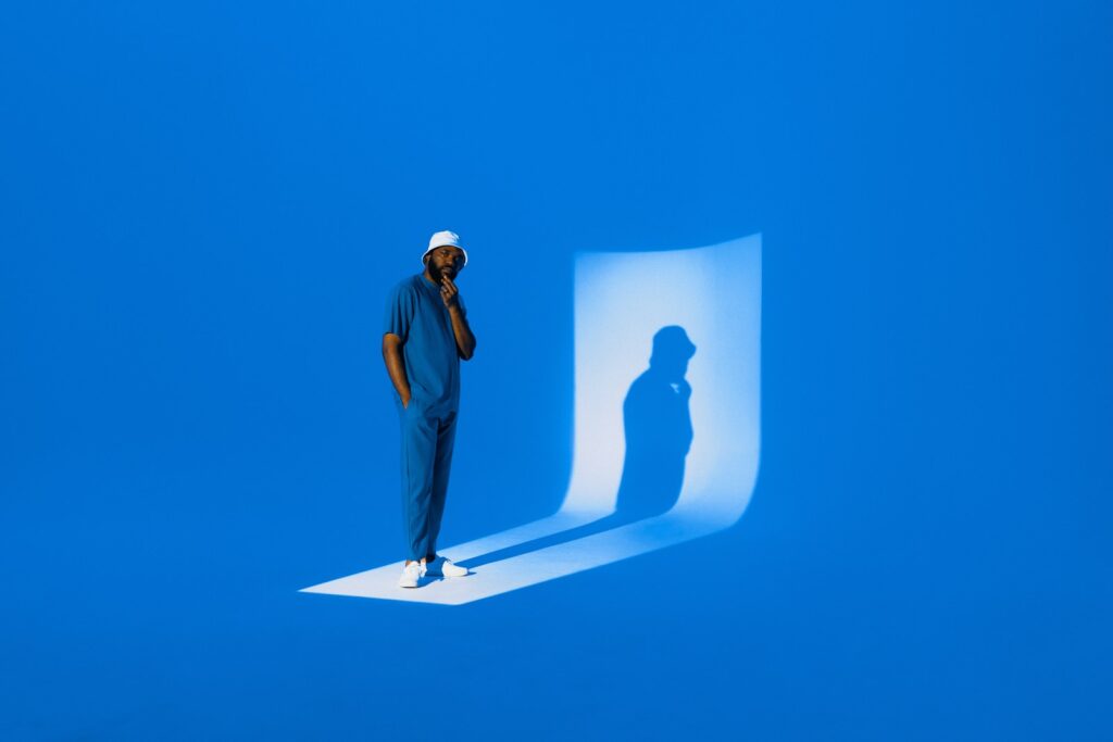 A man casts a shadow on a blue background.